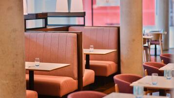 Ein Restaurantinneres mit Sitzboxen und Tischen, an einigen stehen Wassergläser.