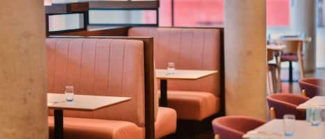 Un interior de restaurante con cabinas y mesas, algunas con vasos de agua.