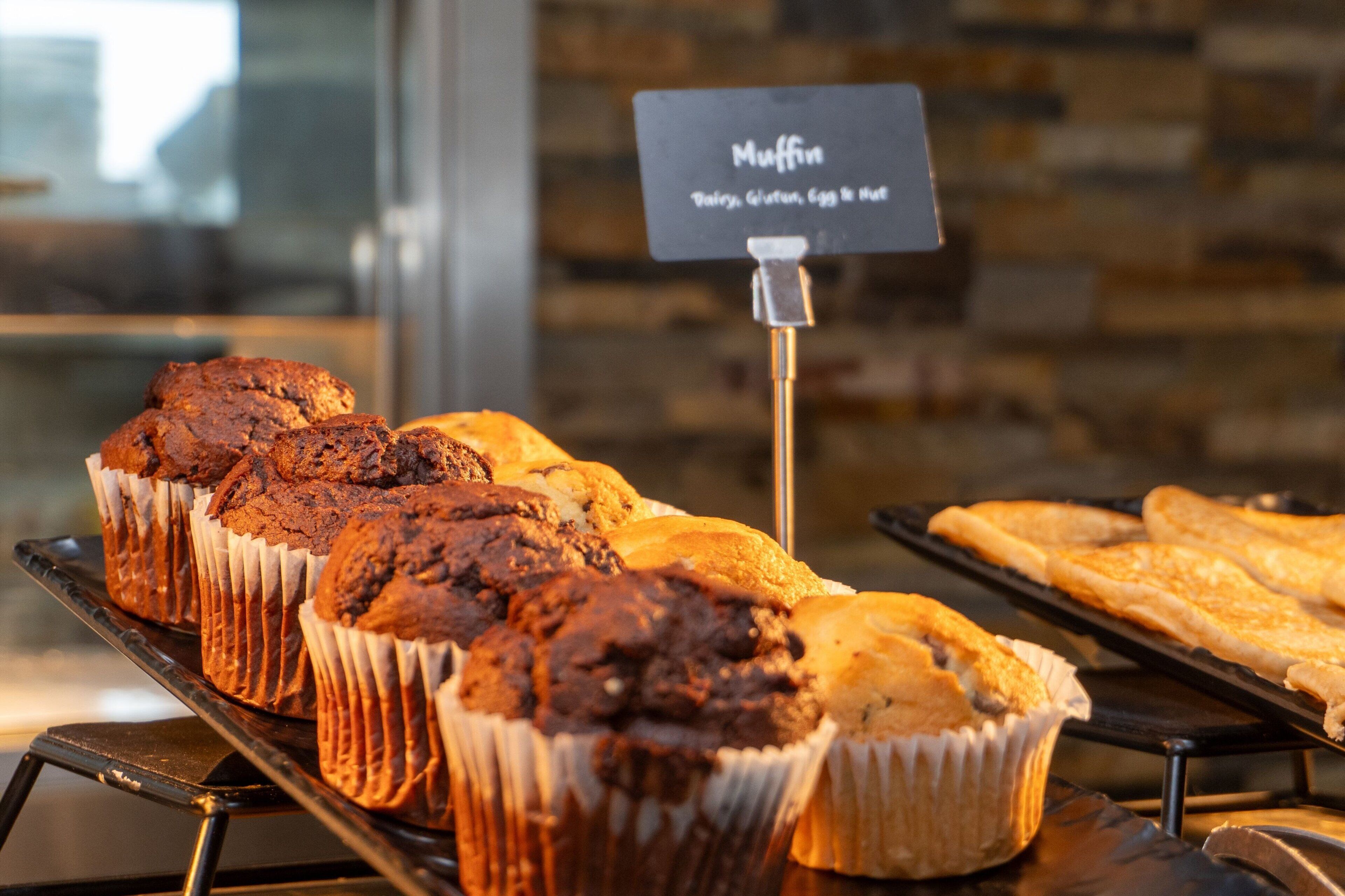 A display of muffins and pastries on a metal rack with a sign indicating the types of muffins available.