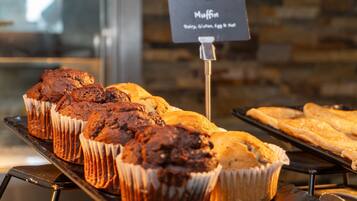 A display of muffins and pastries on a metal rack with a sign indicating the types of muffins available.