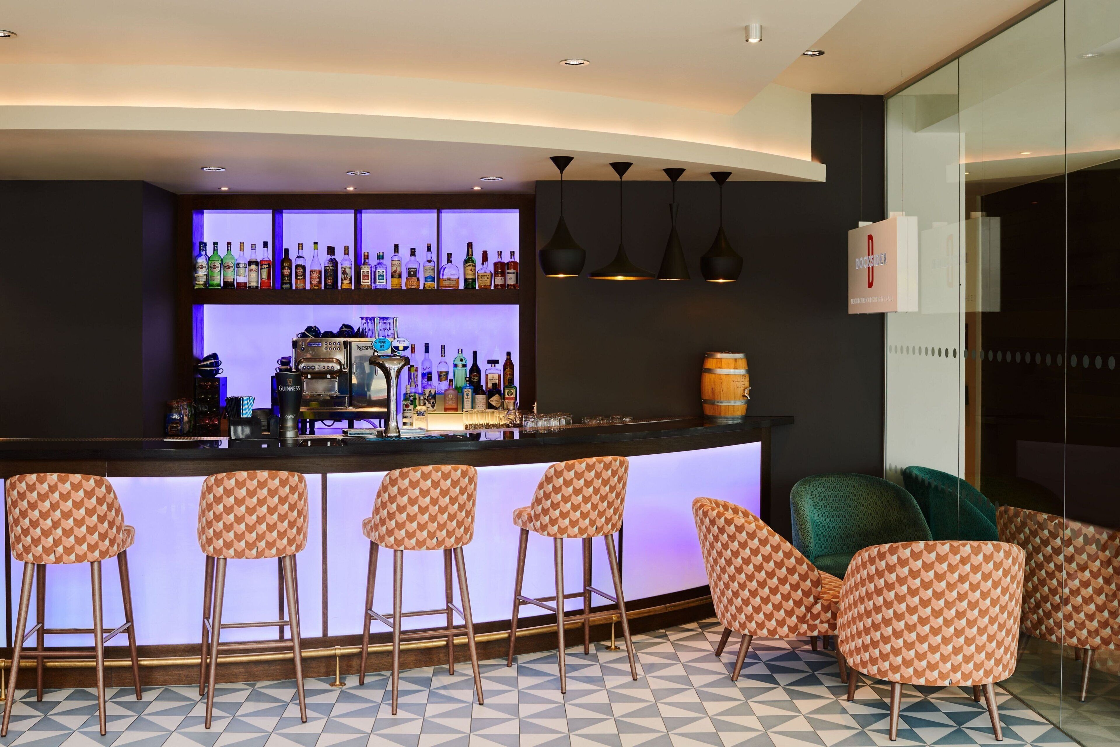 Un espace bar avec un comptoir, des tabourets et un assortiment de bouteilles.