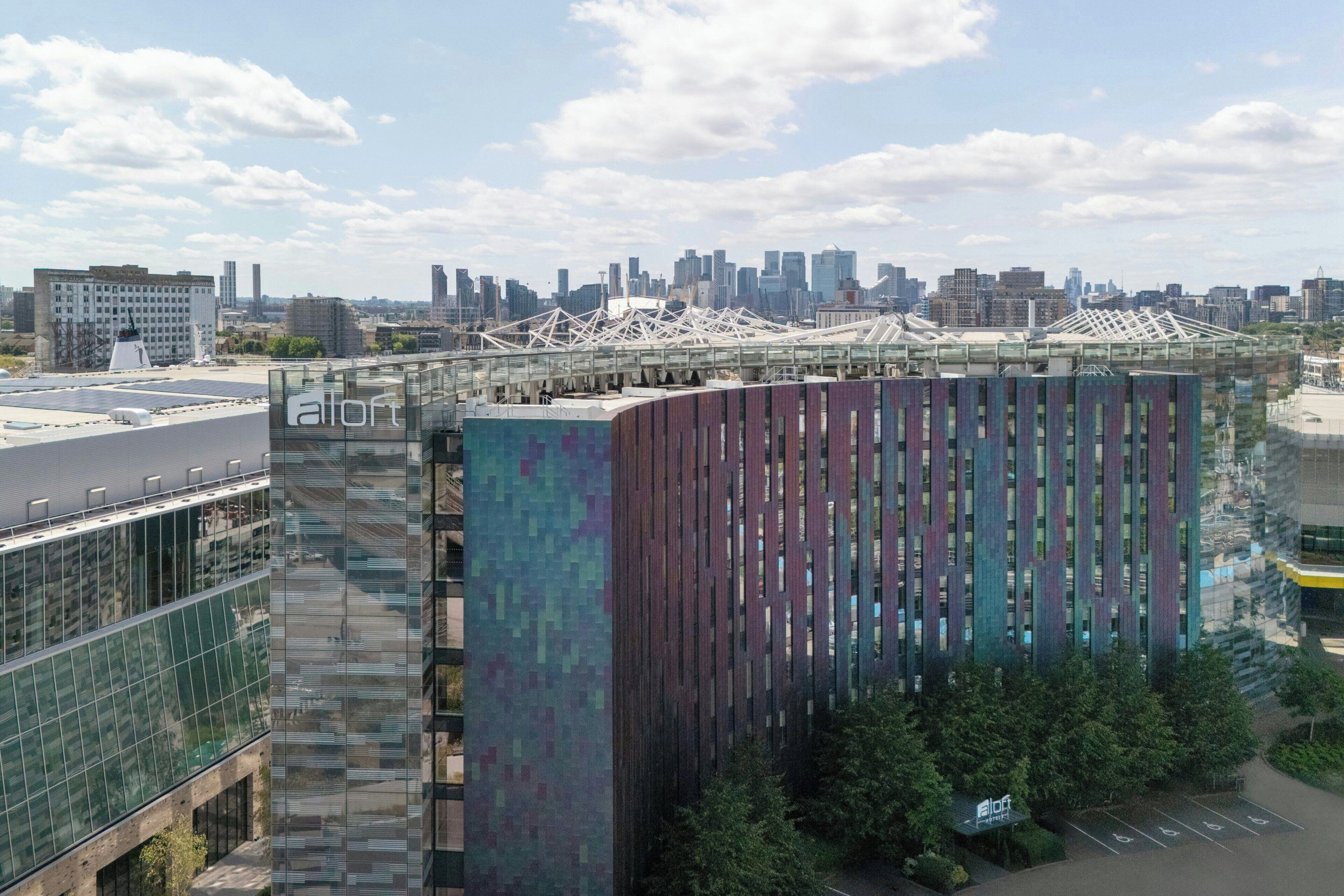 A modern building with a glass facade and a rooftop garden.
