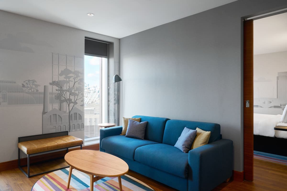A modern living room with a blue sofa, a wooden bench, and a round table.