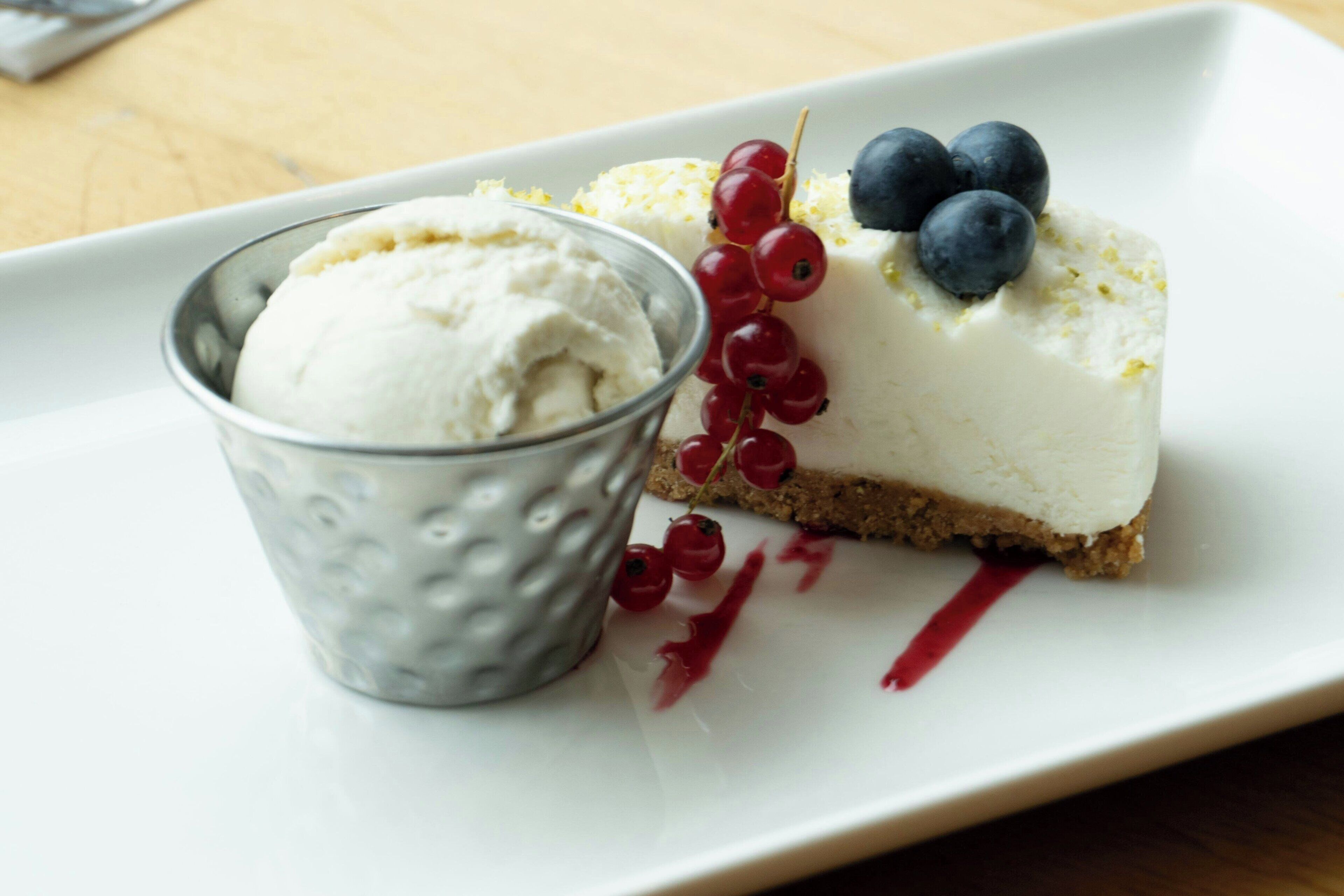 A dessert plate with cheesecake, berries, and a small bowl of ice cream.