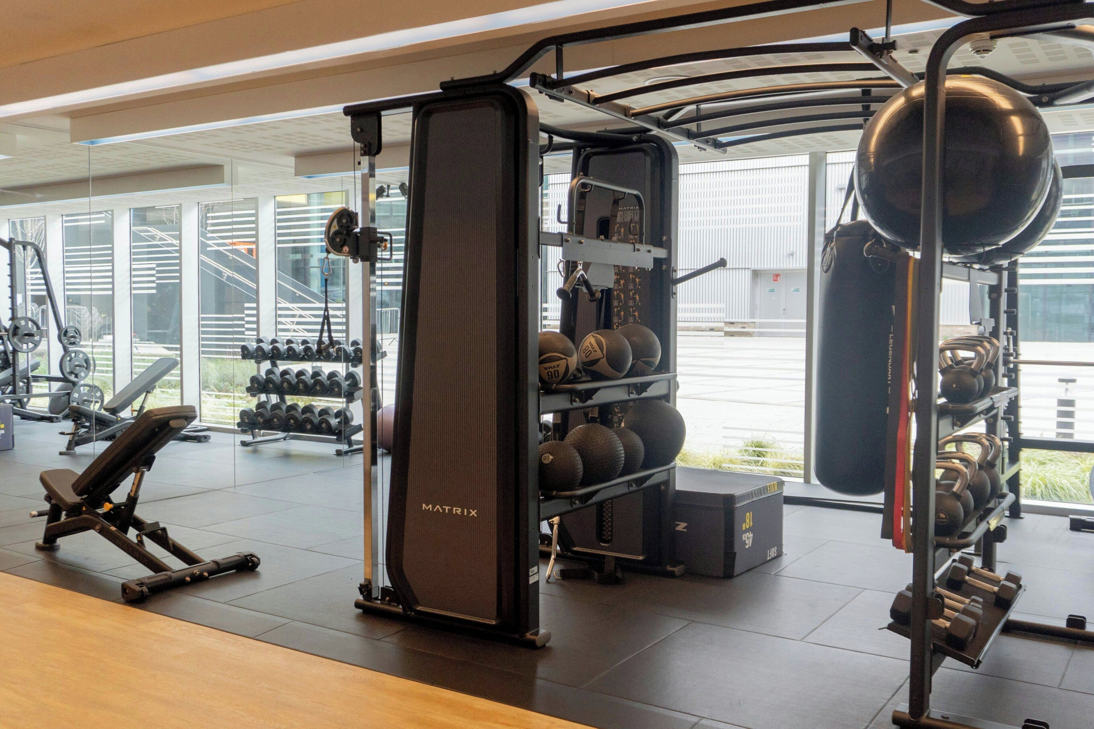 Un gimnasio equipado con máquinas de pesas, mancuernas y pelotas de ejercicio.