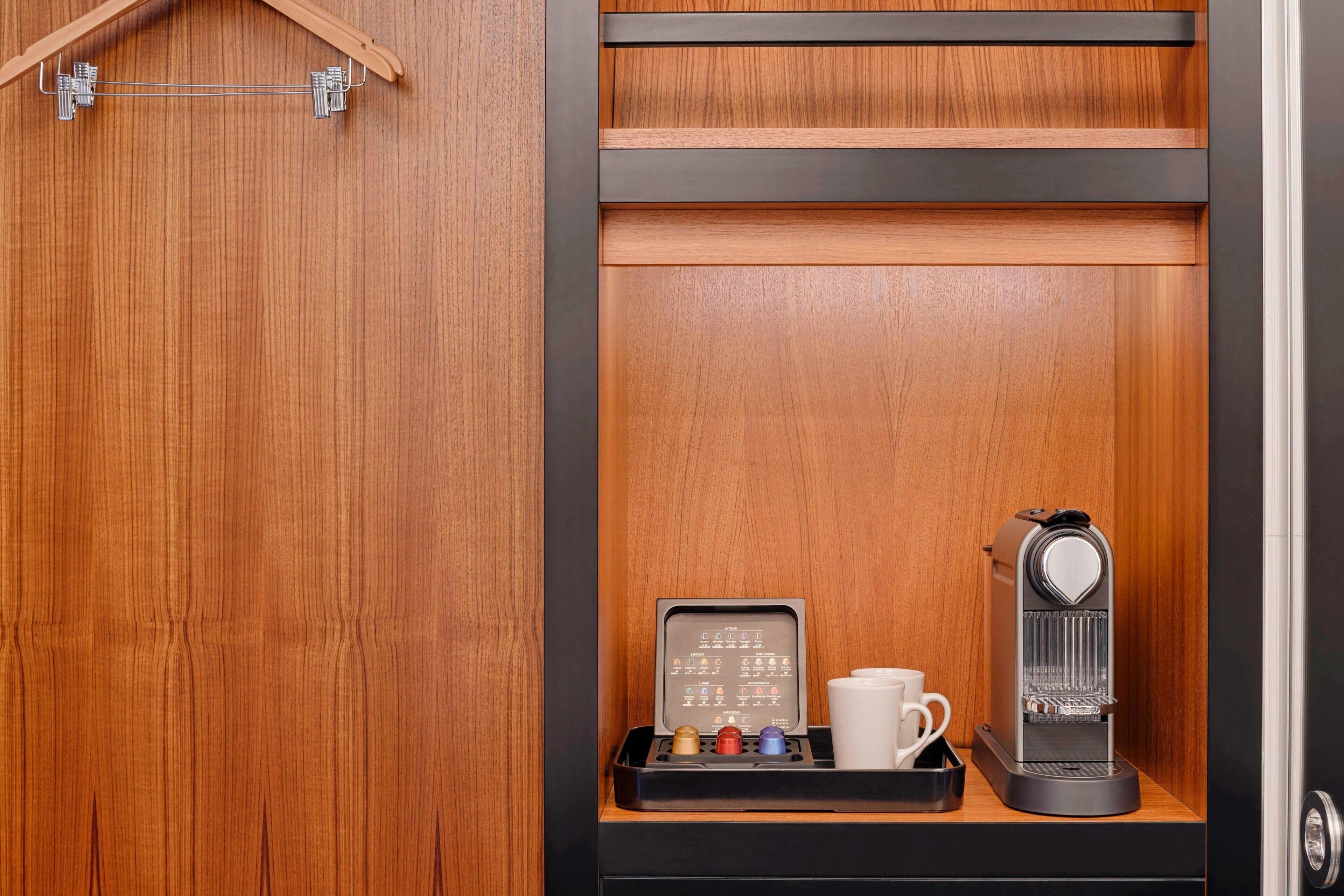 Ein Holzkabinett mit einer Kaffeemaschine und einer Kapselbox für Kaffee.