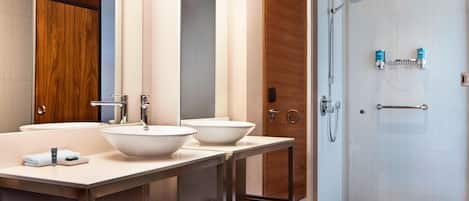 A modern bathroom with two sinks, a shower, and a toilet.