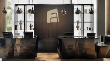 A reception desk area with a modern design, featuring two reception counters, a large window with a view, and a decorative wall with a geometric pattern.