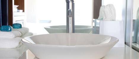 A modern bathroom with a large white basin sink, a faucet, and a mirror.