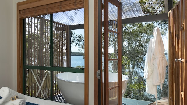 Une chambre avec une grande fenêtre, une baignoire et une vue sur la mer.