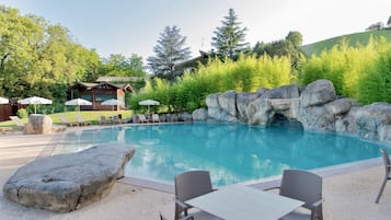 Una piscina al aire libre, sombrillas, sillones reclinables de piscina