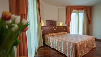 Una habitación de hotel con cama, cortinas, mesita de noche y un reloj en la pared.