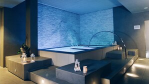 Un moderno espacio de spa con una bañera grande, escalones que la conducen y faroles decorativos.