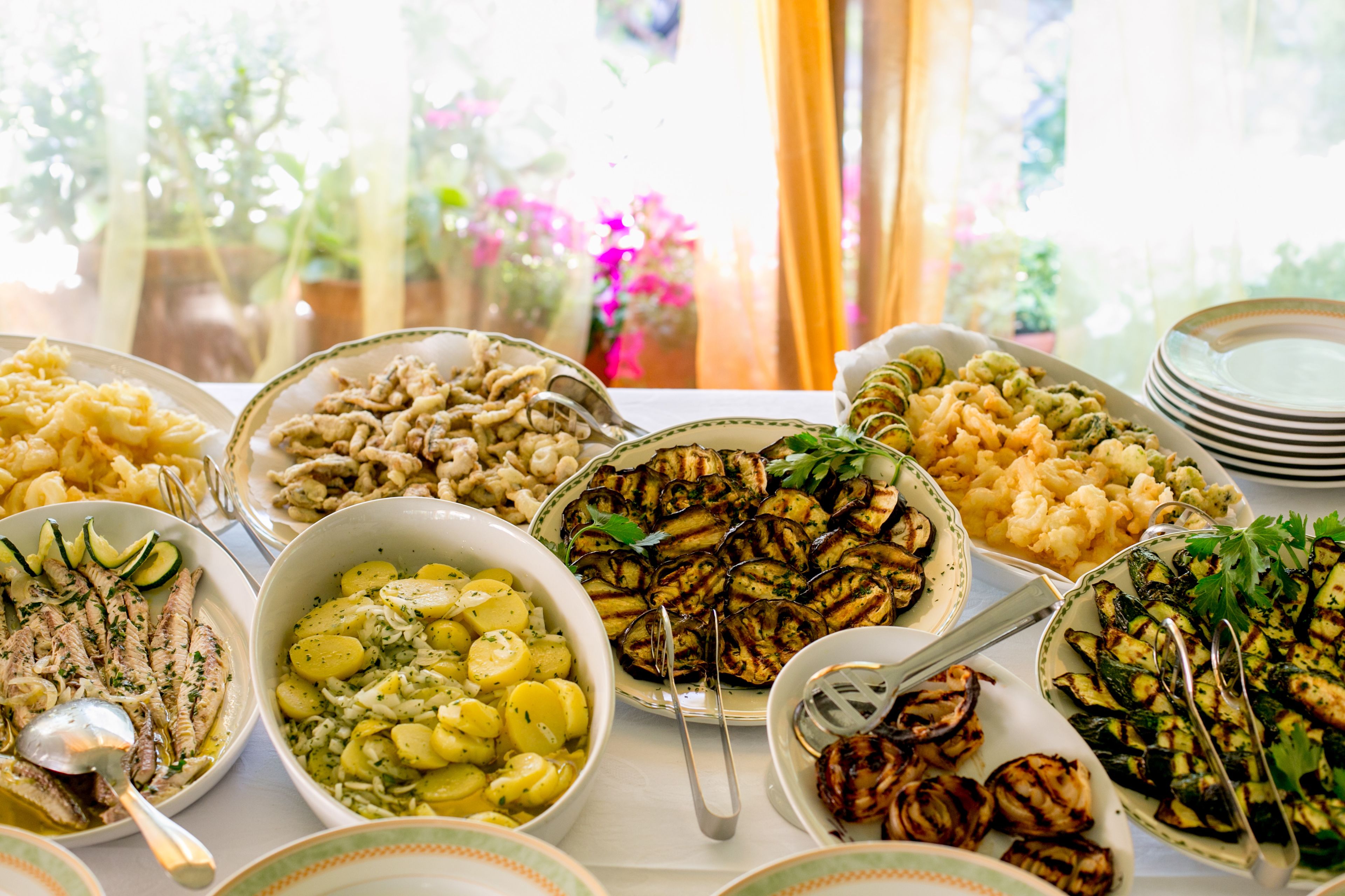 Una mesa con diferentes platos, entre ellos verduras a la parrilla, pasta y ensaladas.