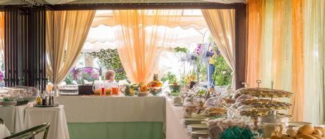A buffet setup with various food items and a table with chairs.