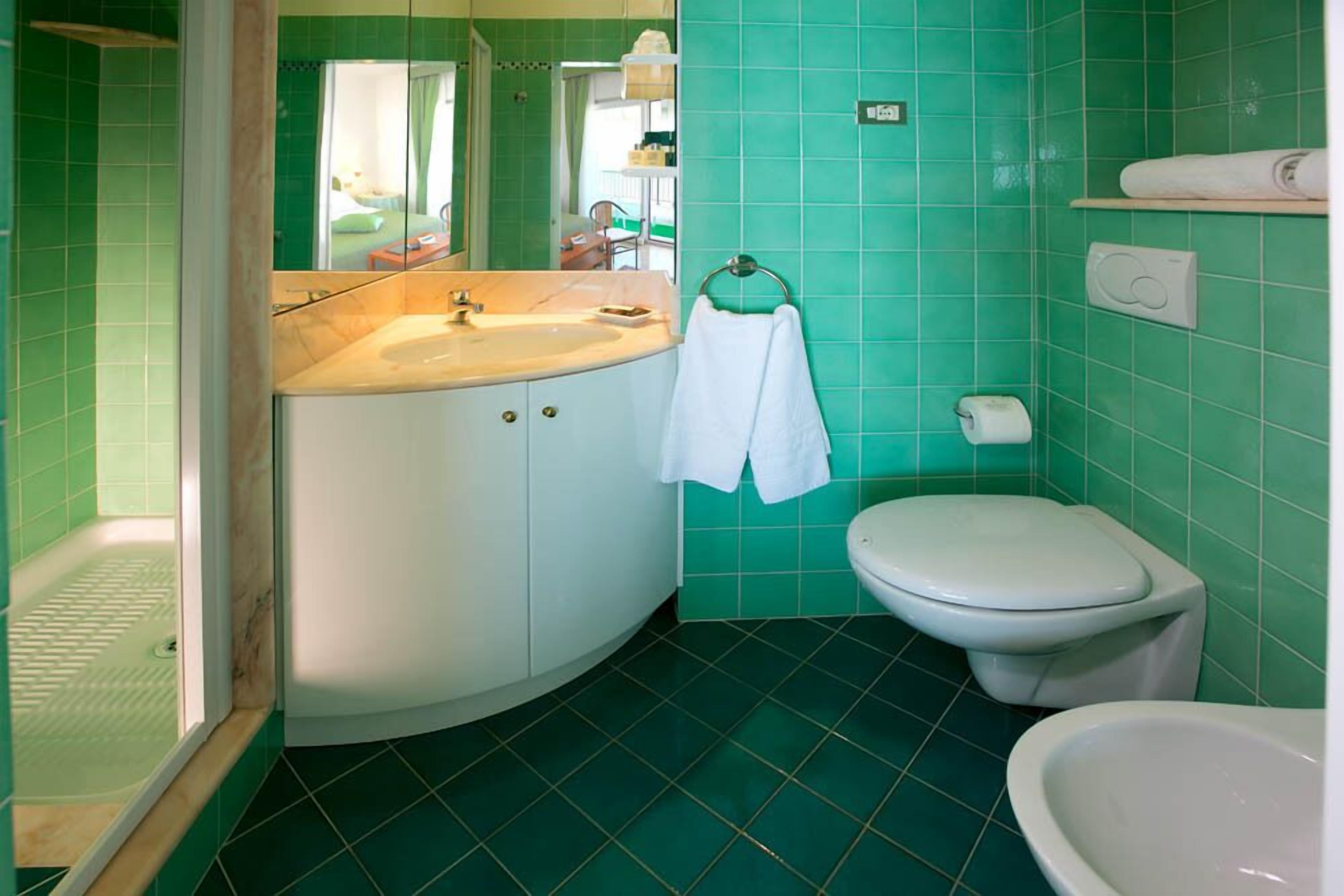 Une salle de bain avec un lavabo blanc, des toilettes et un espace douche.