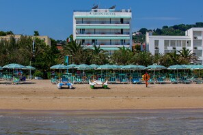 A beach with rows of sun loungers and umbrellas, a lifeguard on duty, and a hotel named "Mion Hotel" in the background. - LH Mion Hotel (Silvi)