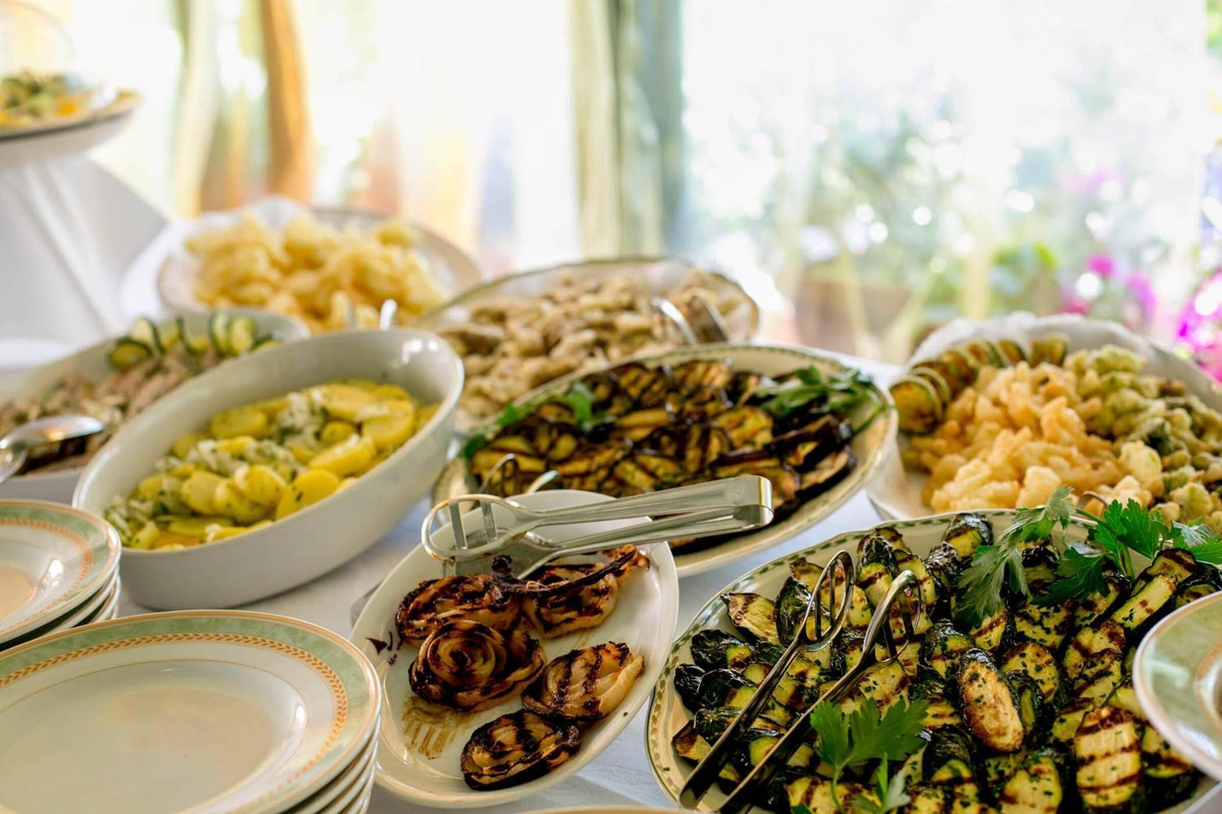Ein Buffet mit verschiedenen Speisen, darunter gegrilltes Gemüse und Salate.