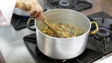 Una olla de acero inoxidable sobre una estufa a gas, con una cuchara de madera removiendo un guiso.