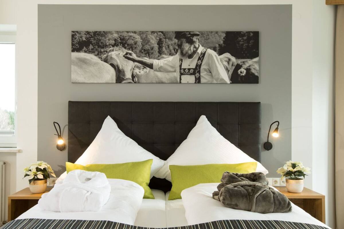 Une chambre d’hôtel avec un grand lit, deux tables de chevet, une tête de lit et un tableau accroché au mur.