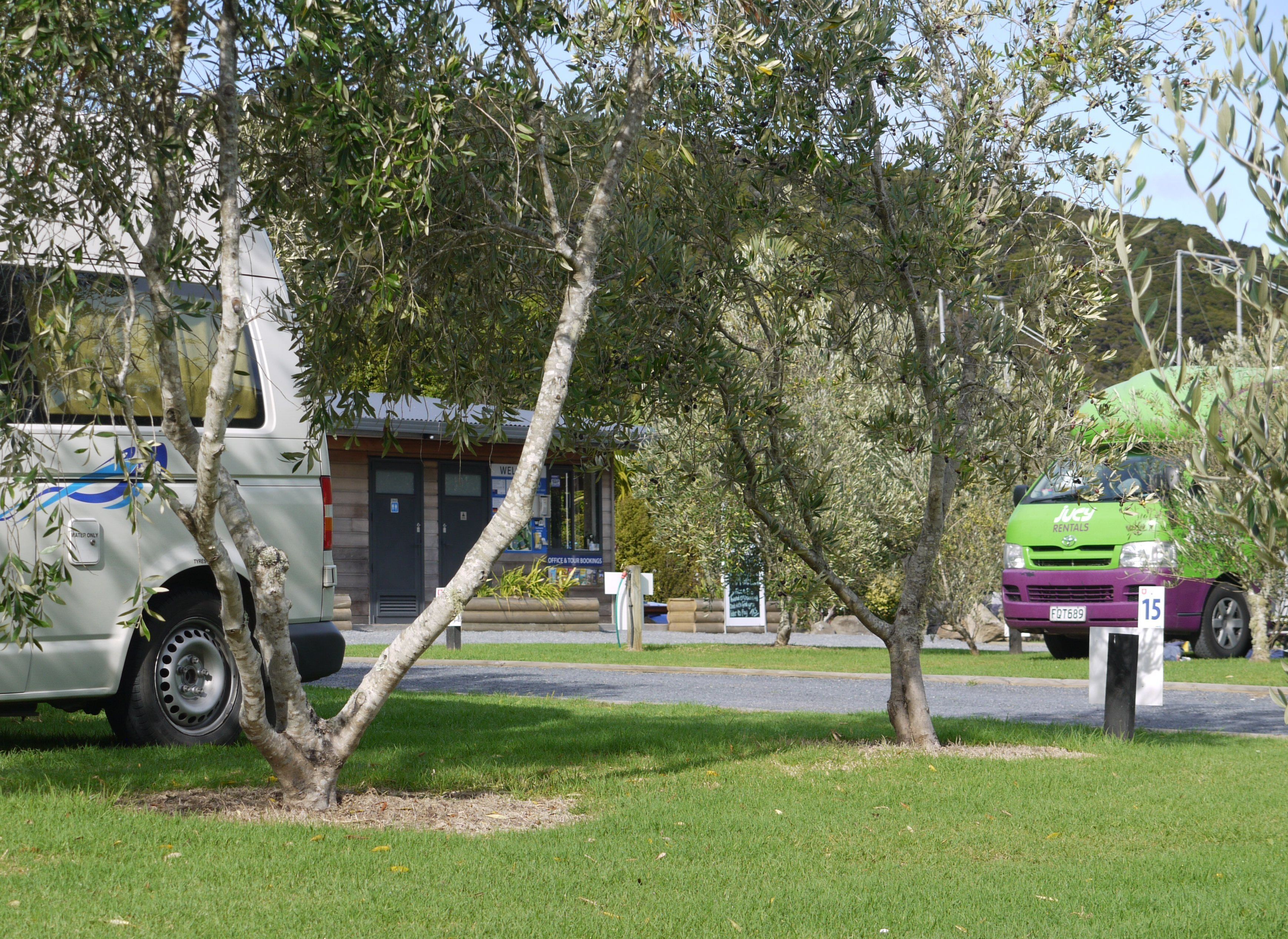 A white van parked next to a building with a sign that reads "Office & Tour Bookings".