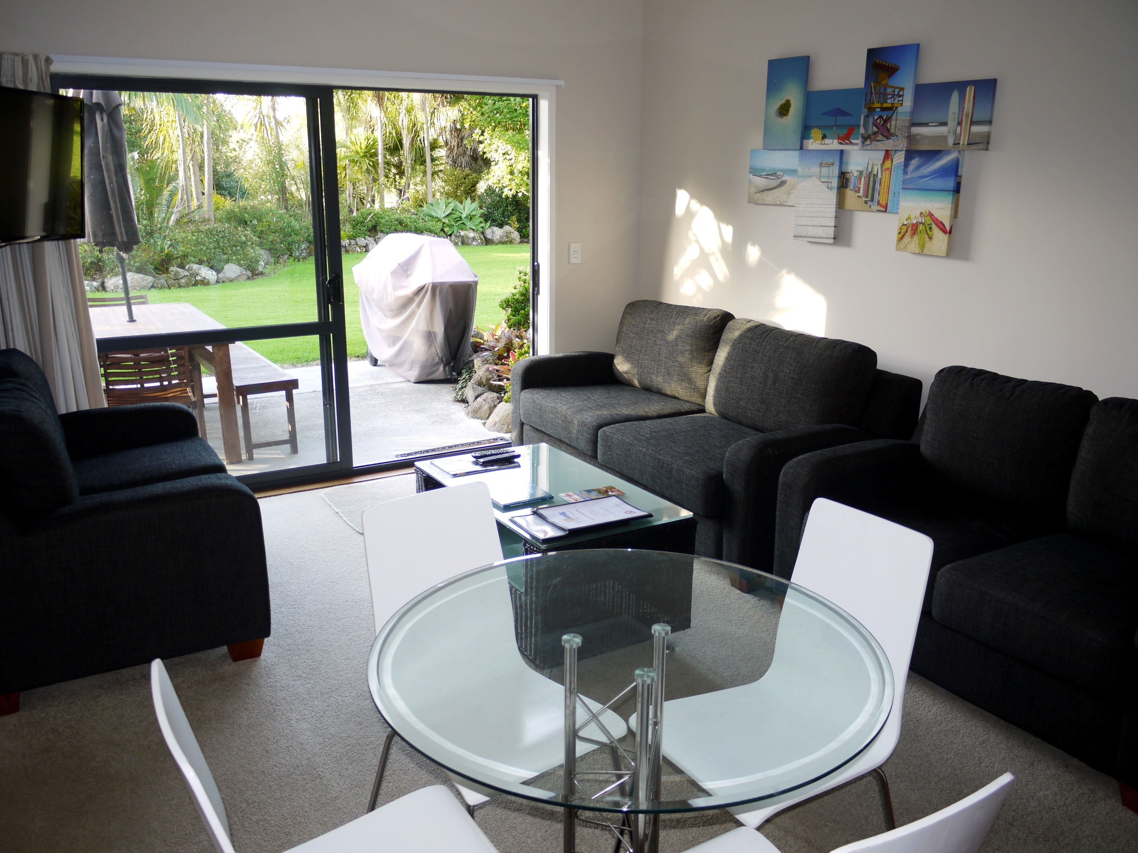 Una sala de estar moderna con una mesa de centro de vidrio, un sofá y una zona de comedor con una mesa y sillas.