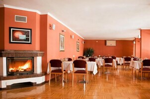 Un comedor con chimenea, mesas dispuestas para comer y sillas.