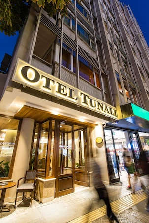 A hotel named "Hotel Tunali" with a prominent illuminated sign, large windows, and a visible entrance.