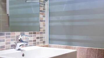 A bathroom with a white sink, a modern faucet, and a mirror above it. The walls are tiled with a mix of colors.