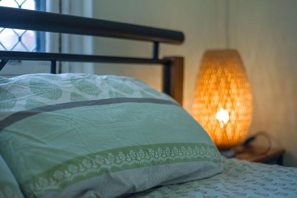 Ein Bett mit einem gemusterten Kopfkissen und einer strukturierten Lampe auf einem Nachttisch.