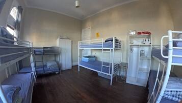 Un dormitorio con literas, un armario, un escritorio con silla y una mesita.