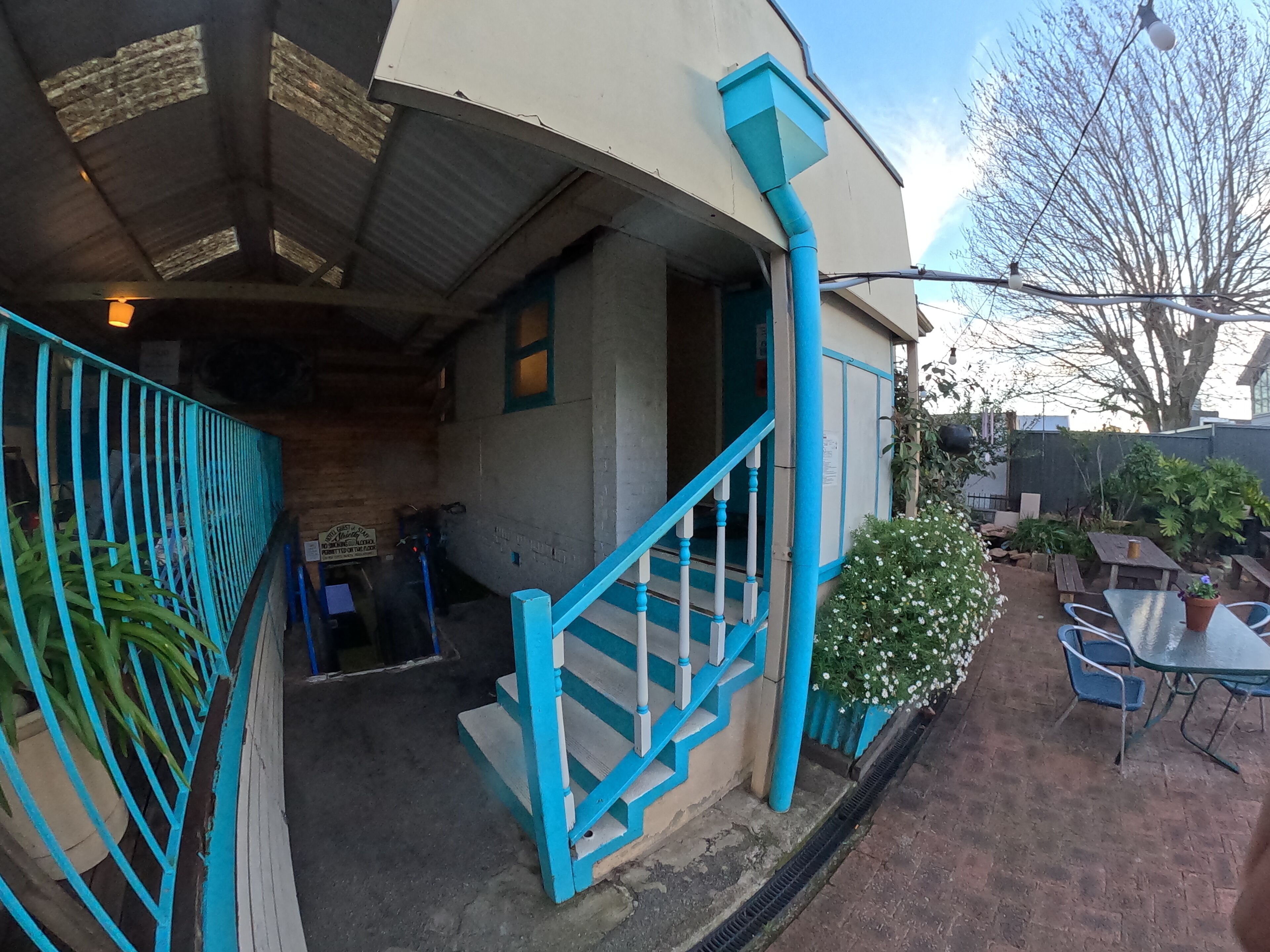 A building with a staircase, outdoor seating, and a garden area.