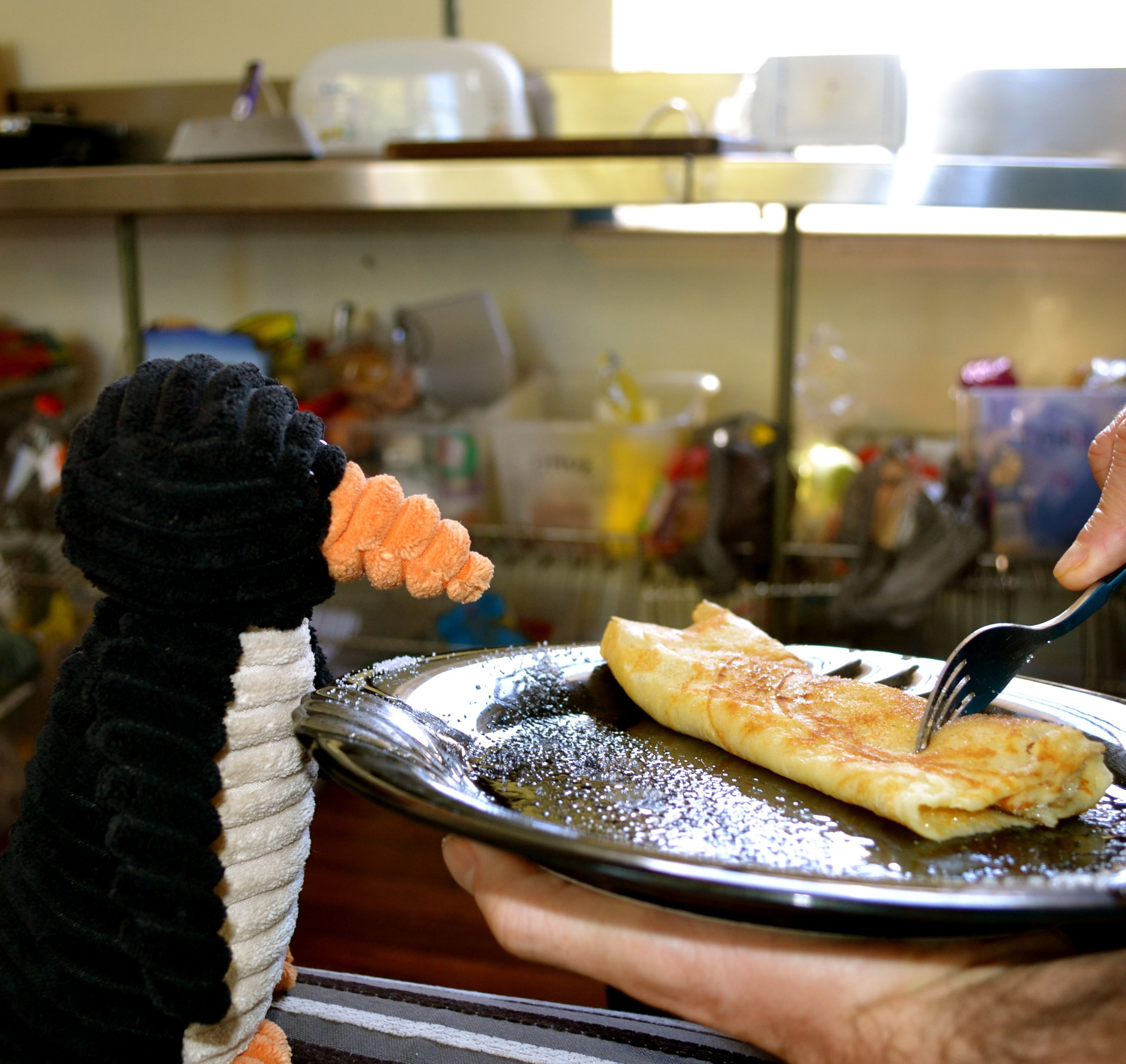 Una persona sosteniendo un plato con un panqueque y un tenedor.