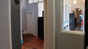 A hallway with wooden flooring, white walls, and blue trim. There are two arched doorways leading to other rooms. - 1849 Backpackers Hotel (Albany)