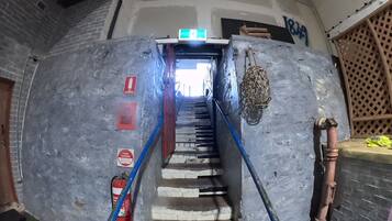 Una escalera que conduce a un nivel superior, con extintor y botiquín en la pared.