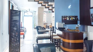 Una sala de estar moderna con un sofá de cuero negro, una mesa de centro de vidrio y una zona de bar de madera curva.