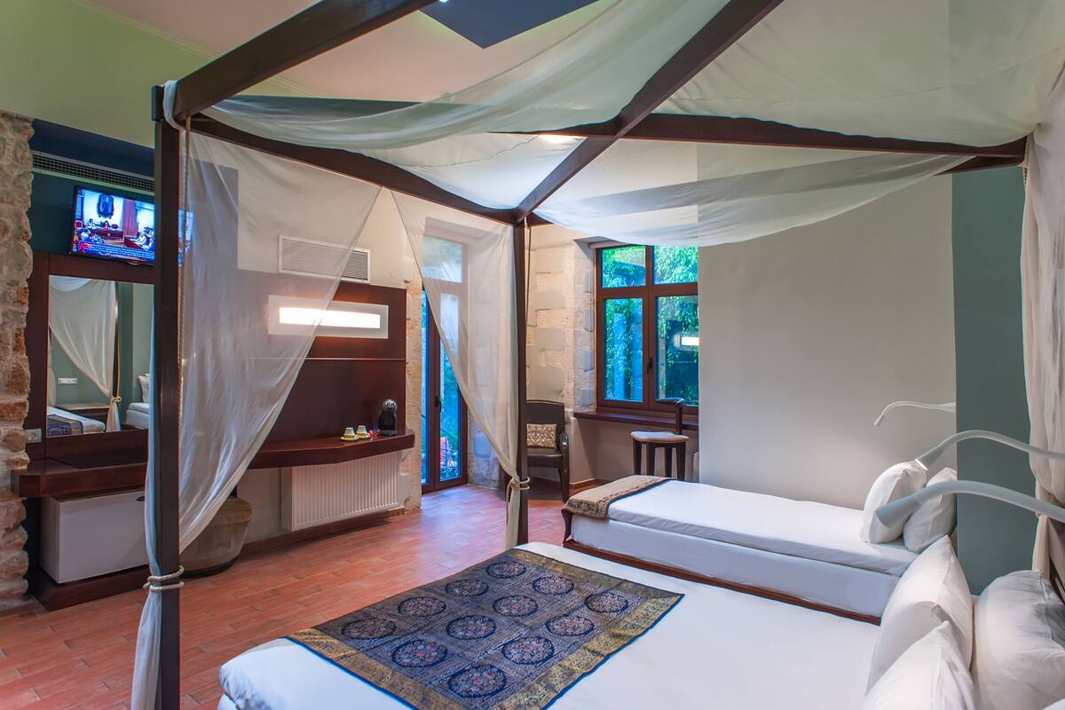 Un lit à baldaquin à quatre poteaux avec vue sur l’extérieur, un petit bureau et une chaise.