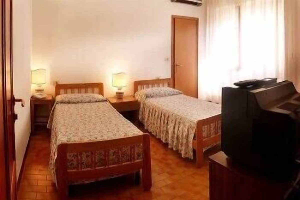 A room with two wooden beds, a television on a stand, and a door.