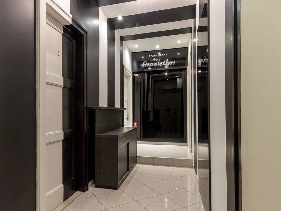 A modern hallway with a reception desk, a sign for 'Apartments Asparathos', and a door marked with the number '1'.
