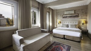 Ein Hotelzimmer mit einem Bett, einem Sofa, einem Teppich und einem Vorhangfenster.