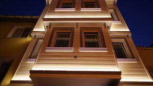 Ein mehrgeschossiges Gebäude mit einer symmetrischen Fassade, das gleichmäßig verteilte Fenster und einen zentralen Eingang aufweist.