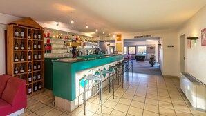 A bar area with a counter, bar stools, and shelves of bottles.