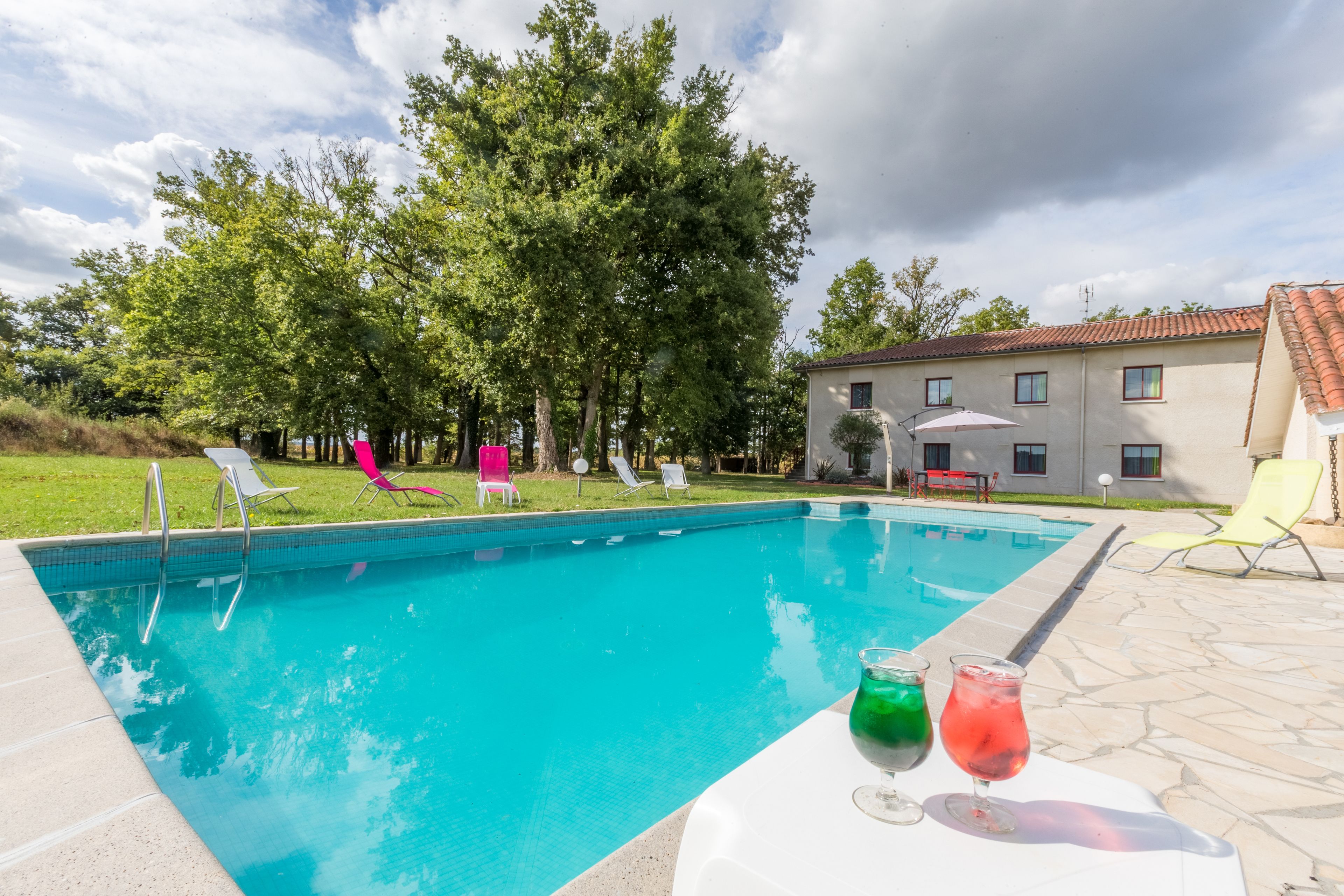 A swimming pool with lounge chairs and a table with drinks.