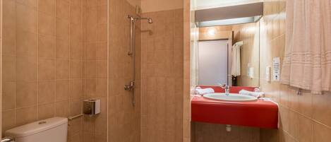 Un baño con ducha, inodoro y lavamanos con encimera roja.
