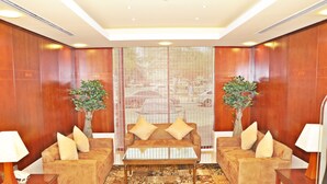 A modern lobby with a sofa set, two side tables, a patterned rug, and wooden paneling. - Ramee Royal Hotel Apartments (Abu Dhabi)