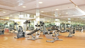 A gym with various exercise equipment, mirrored walls, and a wooden floor. - Ramee Royal Hotel Apartments (Abu Dhabi)