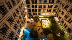 Ein Poolbereich auf dem Dach mit einer runden Wasserspüle, umgeben von Palmen und Liegestühlen.