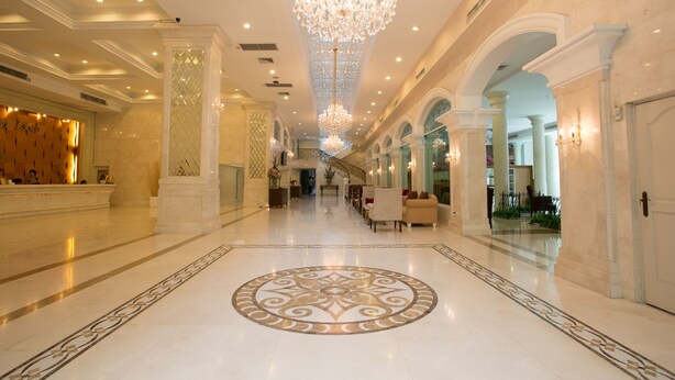 Eine großzügige Lobby mit einem prunkvollen Kronleuchter, Marmorböden und klassizistischer Architektur.