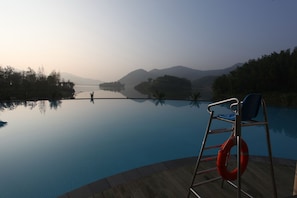 A serene pool area with a clear view of distant mountains and a calm lake.