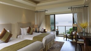 Habitación de hotel con dos camas, una zona de comedor y vista al agua.